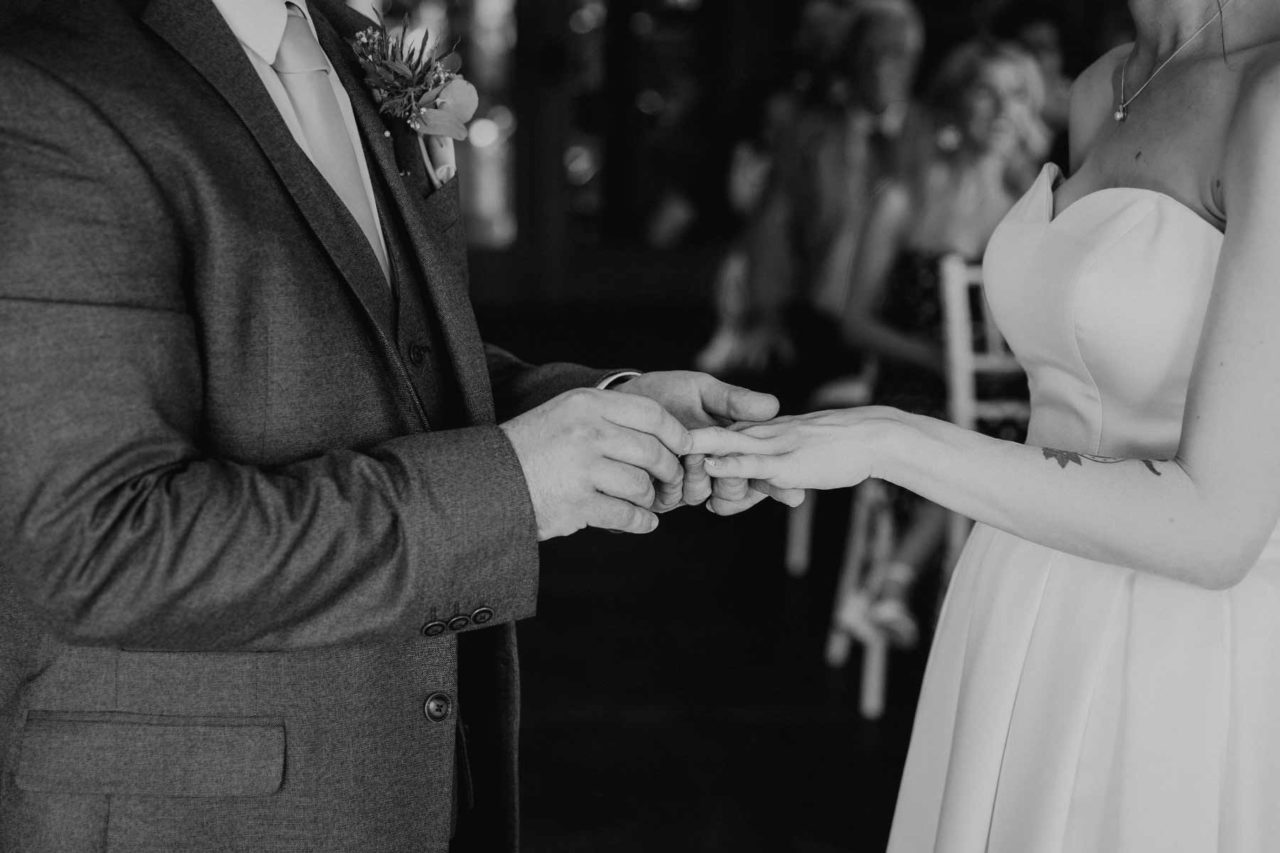 Detail shot of groom placing ring onto his bride's finger