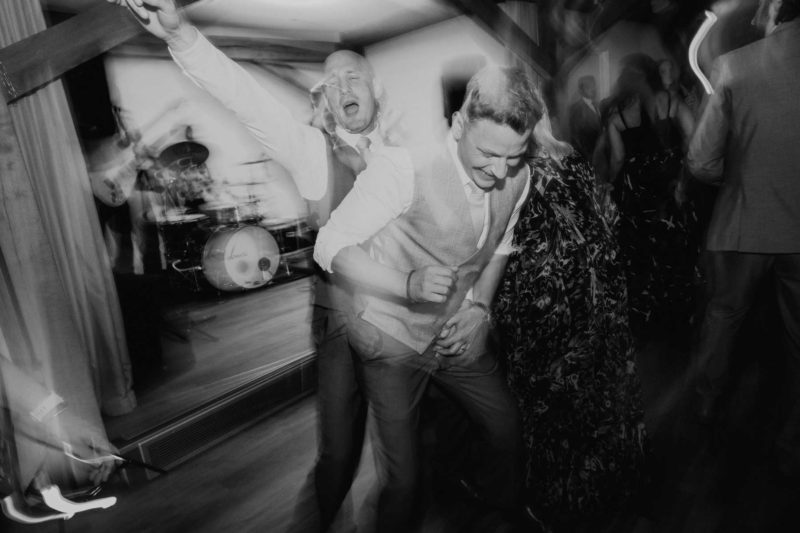 Black and white shot of groom and best man dancing and having fun