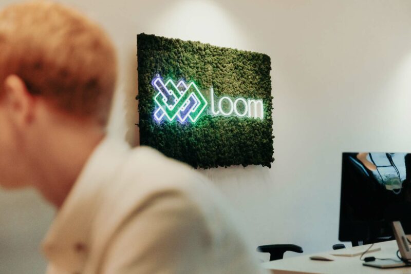 Loom digital neon LED sign behind a company employee. Shot in the Loom offices in Bristol.
