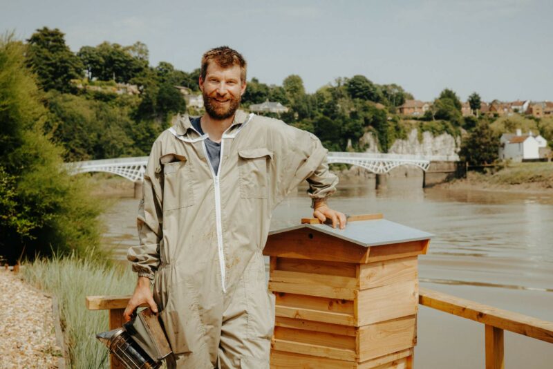 Portrait of bee keeper. Director and Co-Founder of Wye Vallery Meadery. Shot against the River Wye in Chepstow on a sunny day in August 2024.