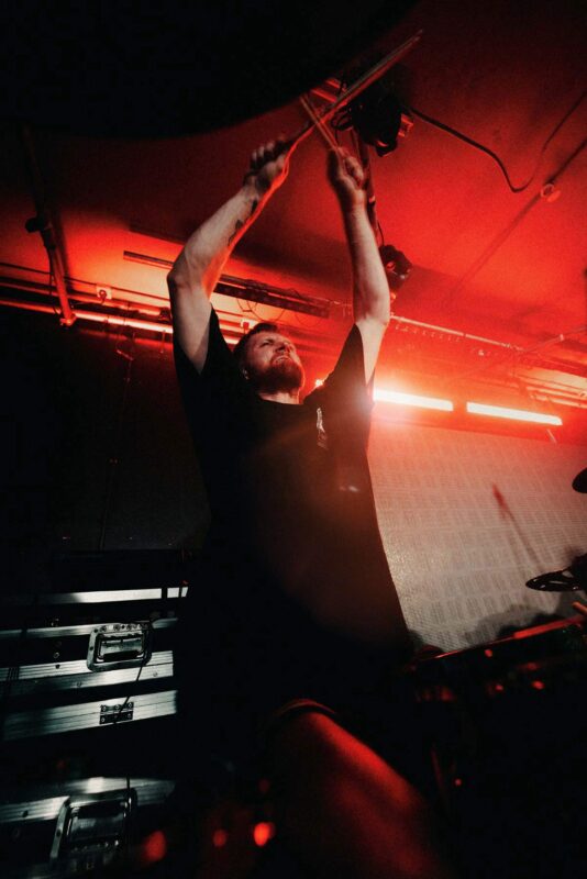 CONTINENTS drummer Scott on stage with his arms above his head, mid beat. Shot at the Wellington Rooms, Hull.