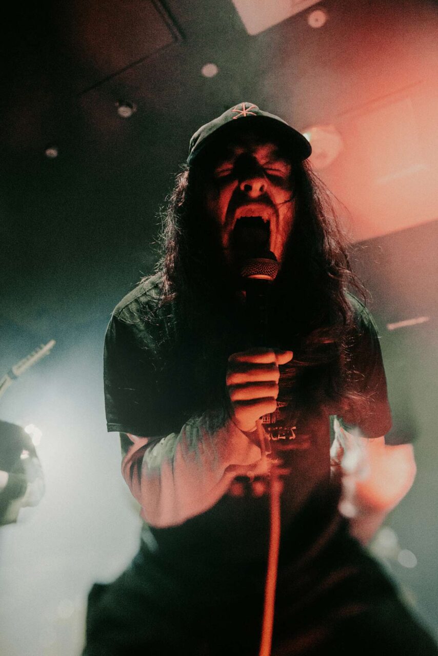 Struggler frontman Ieuan on stage at Bridgend's Black Cat venue, screaming into a microphone.